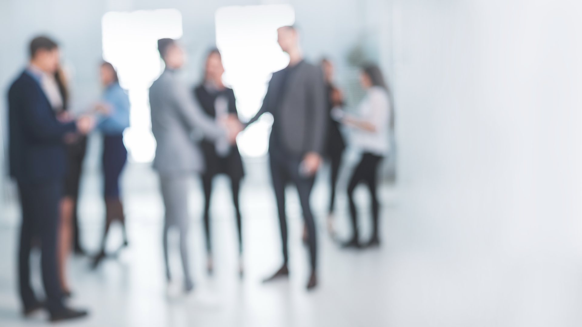 Blurred image of a group of people standing around talking